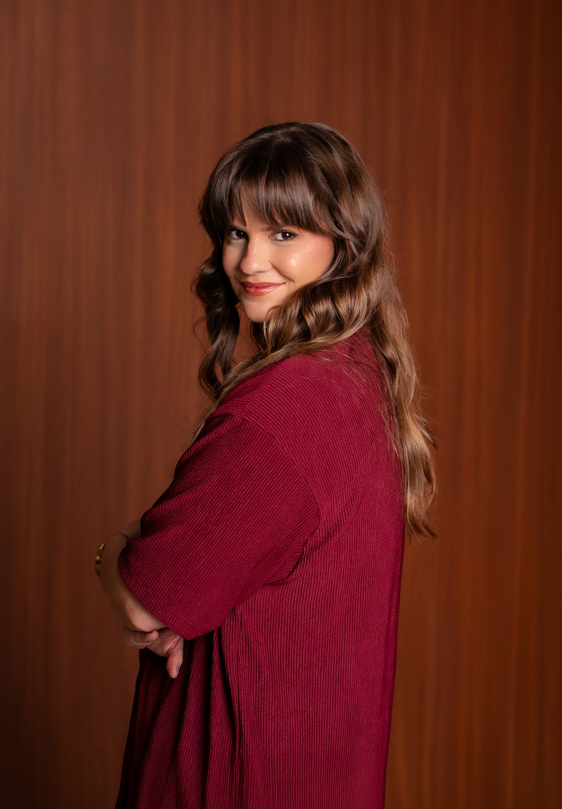 Paola Z. Behs, de blusa vinho, olhando para a câmera